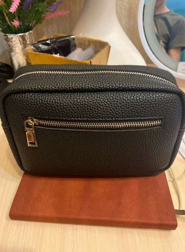Bolso cosmético negro texturizado con cremallera dorada, ideal para maquillaje y viajes